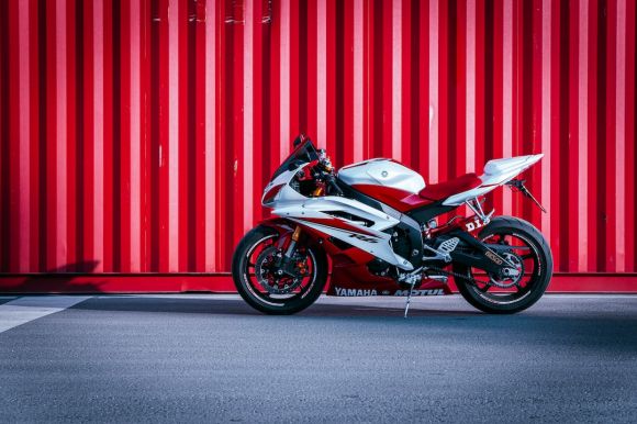 Motorcycle - black and white sports bike parked beside red wall