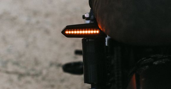 Moto Riding - Closeup of black metal motorcycle with soft saddle and red taillight parked on road