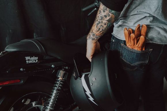 Moto Gloves - person in brown jacket and blue denim jeans riding on motorcycle
