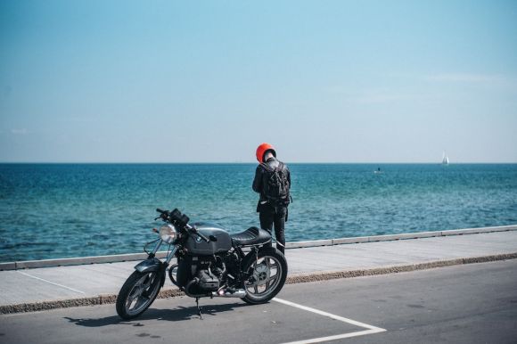 Motorcycles Backpack - person standing beside motorcycle near body of water