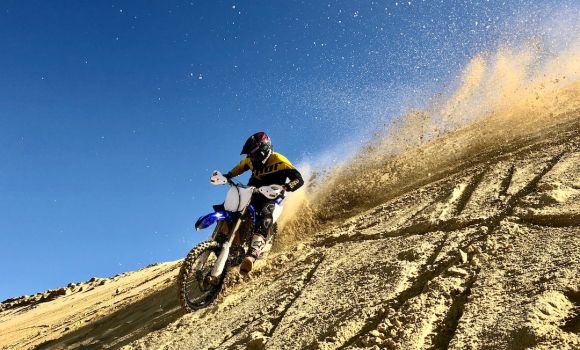 Motorcycle Helmet - man riding motocross dirt bike on brown sand during daytime