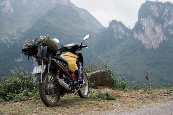 Motorcycle Trip - red motorcycle parked near the rock front of the high mountain