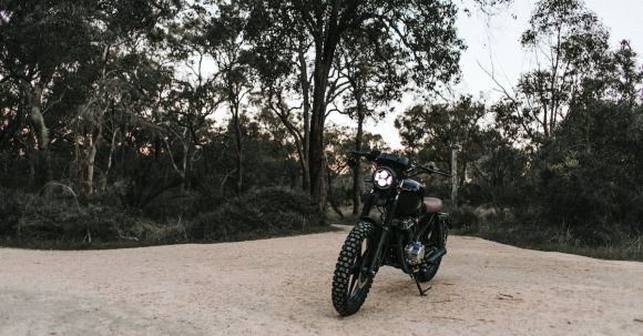 Moto Riding - Motorbike parked on sandy ground near trees and plants under blue cloudless sky in summer sunny day