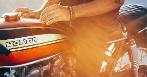 Speed Confidence - Crop anonymous young tattooed male biker in casual clothes sitting on modern motorcycle on asphalt road on sunny day