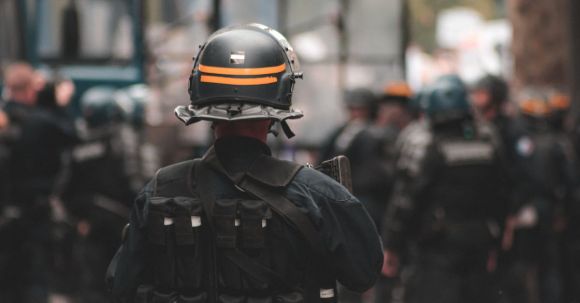 Maintain & Clean Helmet - Back view of anonymous policeman in helmet and bulletproof vest maintaining law and order while standing on city street