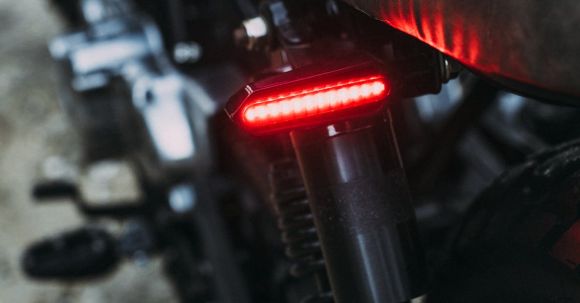Moto Riding - Closeup of modern motorcycle with red taillight and soft saddle parked on road
