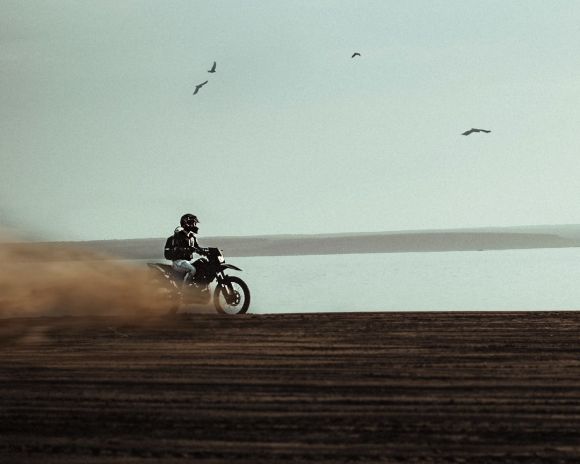 Motorcycle - man riding on dirt bike near body of water