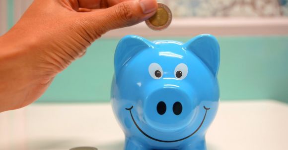Save Money - Person Putting Coin in a Piggy Bank