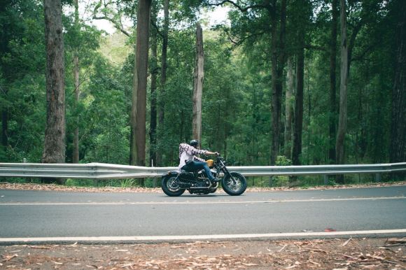 Moto Riding - person riding motorcycle passing on road surround by trees