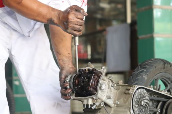 Motorcycle Maintenance - a man working on a motorcycle with a wrench