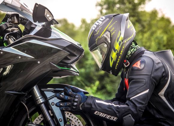 Moto - person wearing helmet while holding motorcycle