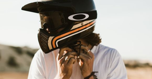 Motorcycle Safety - Anonymous ethnic biker with in white shirt and black helmet with tattoos on arms on blurred background