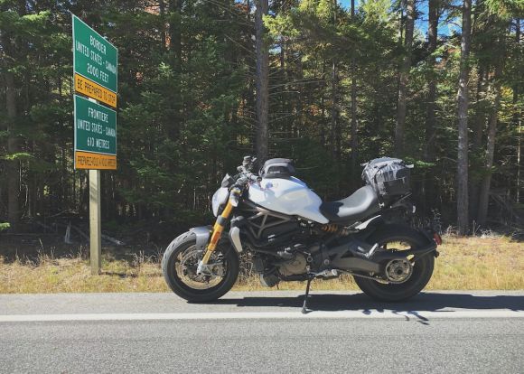 Motorcycle Insurance - parked gray motorcycle beside road signs during daytime