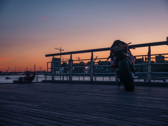 Moto Jackets - a person sitting on a bench at sunset