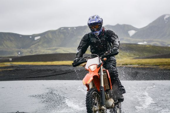 Moto Jacket - person riding dirt motorcycle on body of water during daytime