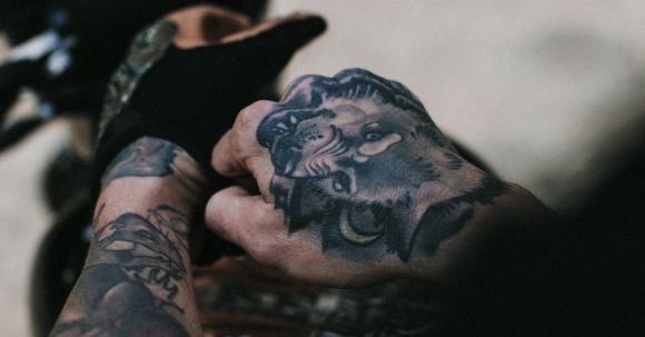 Motorcycle Gear Essentials - From above of crop anonymous man with tattooed hands wearing leather gloves before riding motorcycle