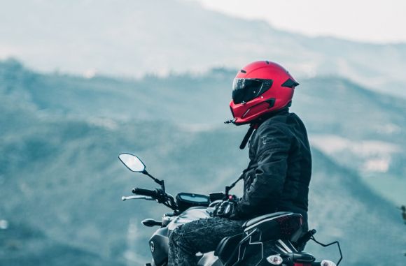 Motorcycle Helmet - a man riding a motorcycle with a mountain in the background