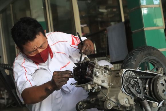 Motorcycle Maintenance - a man working on a motorcycle in a garage