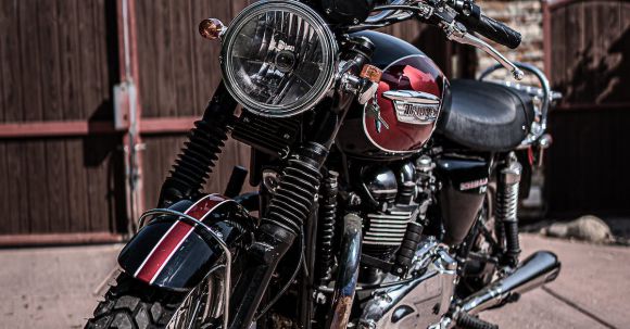 Moto Riding - Black and red retro motorcycle with chrome details parked on asphalt road against cloudless blue sky