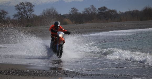 Moto Riding - Unrecognizable motorcyclist riding on motorbike on seashore in twilight