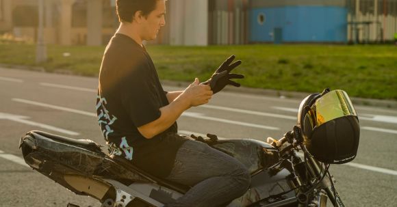 Motorcycle Gloves Selection Tips. - Close-Up Shot of a Man Putting On Gloves while Sitting on a Motorcycle