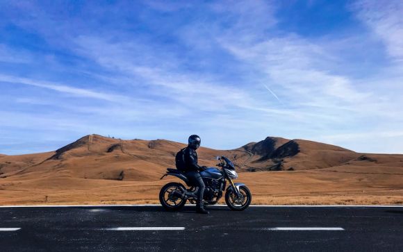 Moto - man riding motorcycle at vast land during daytime