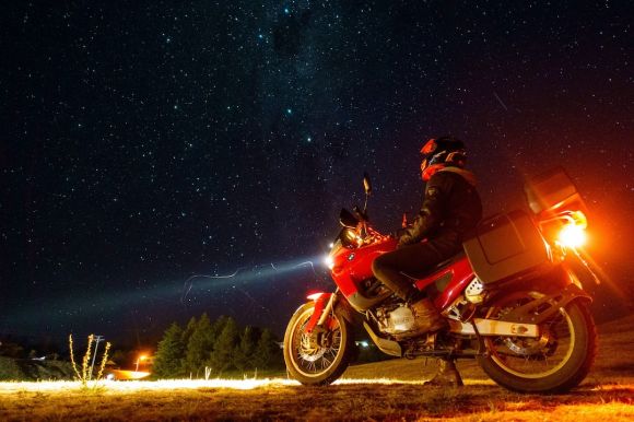 Motorcycle Trip - man in red and black motorcycle suit riding on red motorcycle under starry night