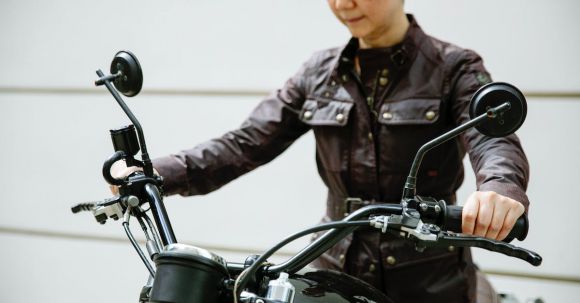 Motorcycle Jeans Essentials. - Crop serious mature Asian female biker in jacket and jeans sitting on black motorcycle in street near wall in daytime